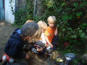 im Garten auf einem Herd aus Ton werden Apfelscheiben in einem Puppentopf geschmort
